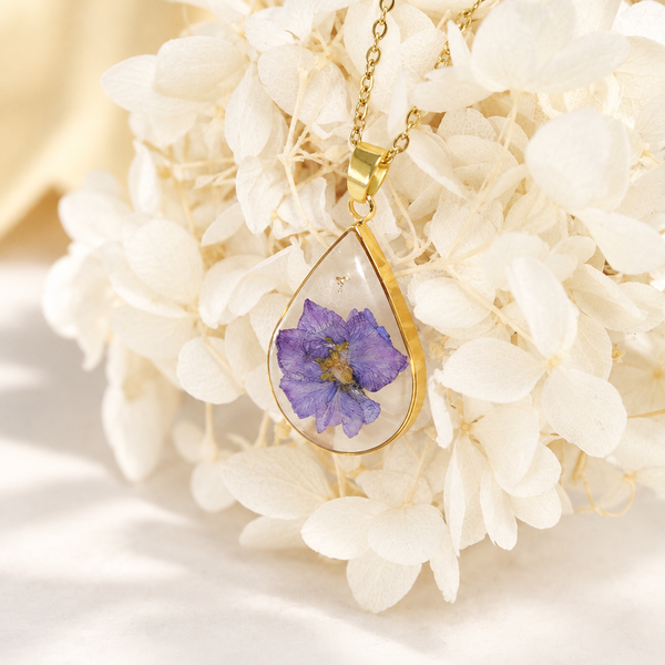 Collar de gota con flor violeta sobre hortensias secas blancas