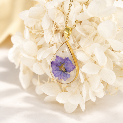 Collar de gota con flor violeta sobre hortensias secas blancas