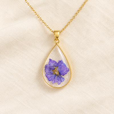 Collar de gota con flor violeta prensada en resina sobre tela de lino
